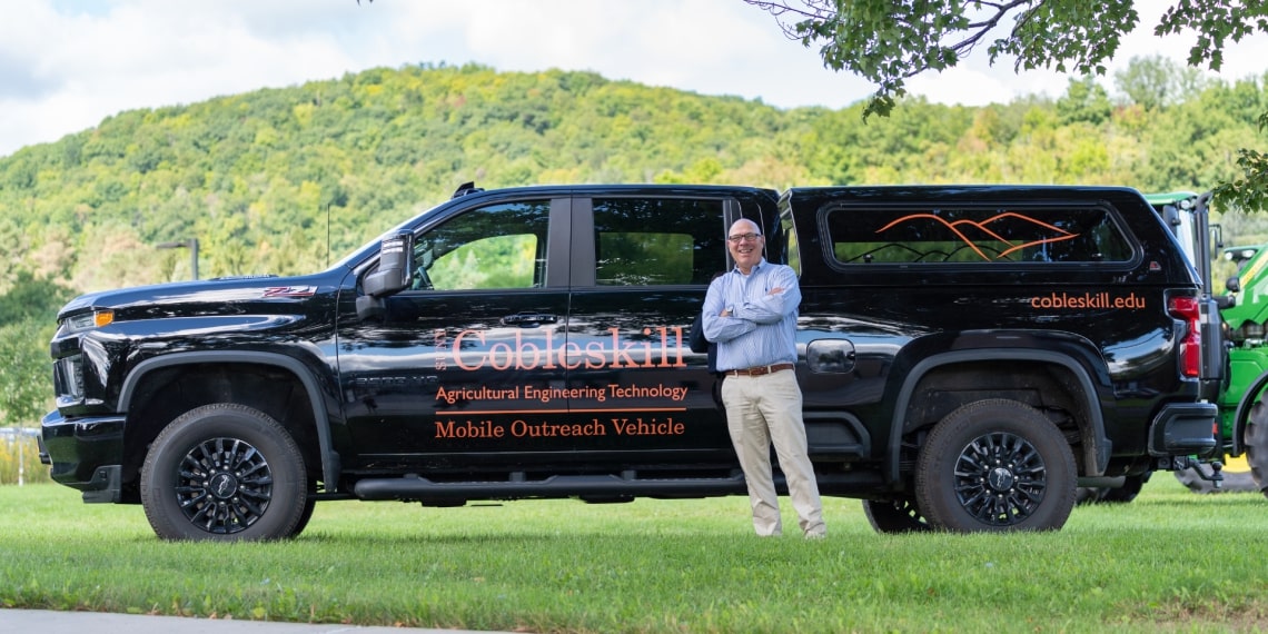 Douglas Hammond standing in front of a branded vehicle. 